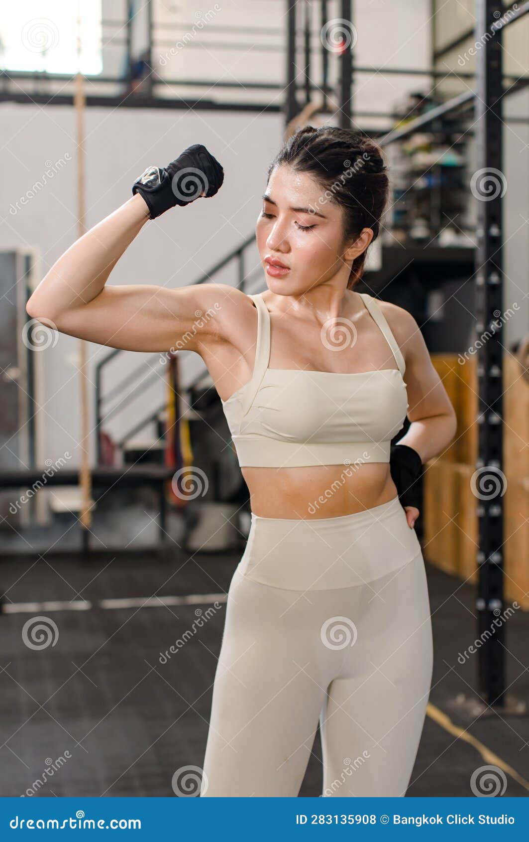 Young fit woman in sports bra and workout pants, wearing boxing