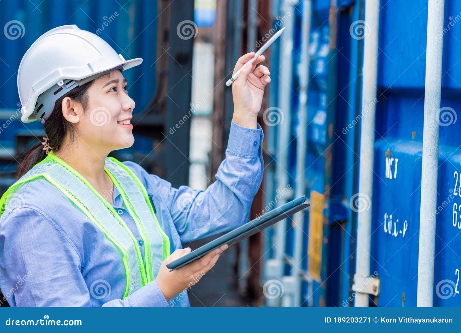 asian young teen working in shipping logistic cargo load area use tablet wireless technology to checking customs detail of import