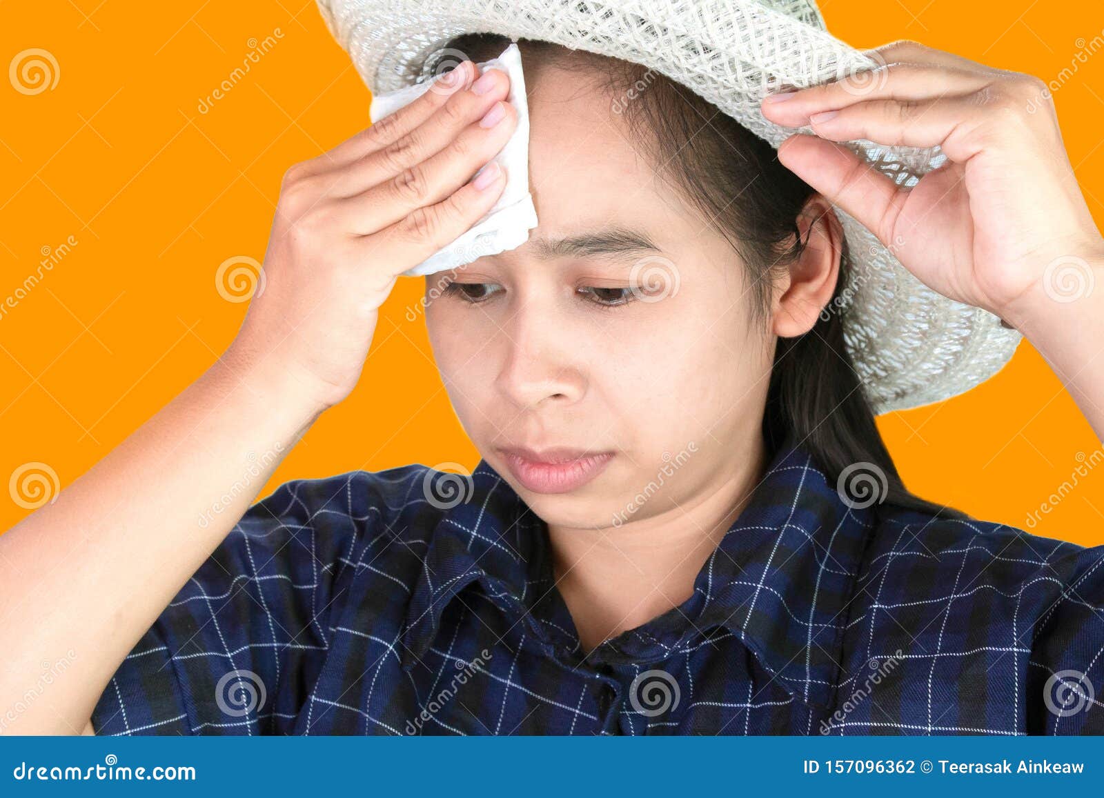 asian young woman uses a tissue to wiped the sweat on her forehead on a hot day