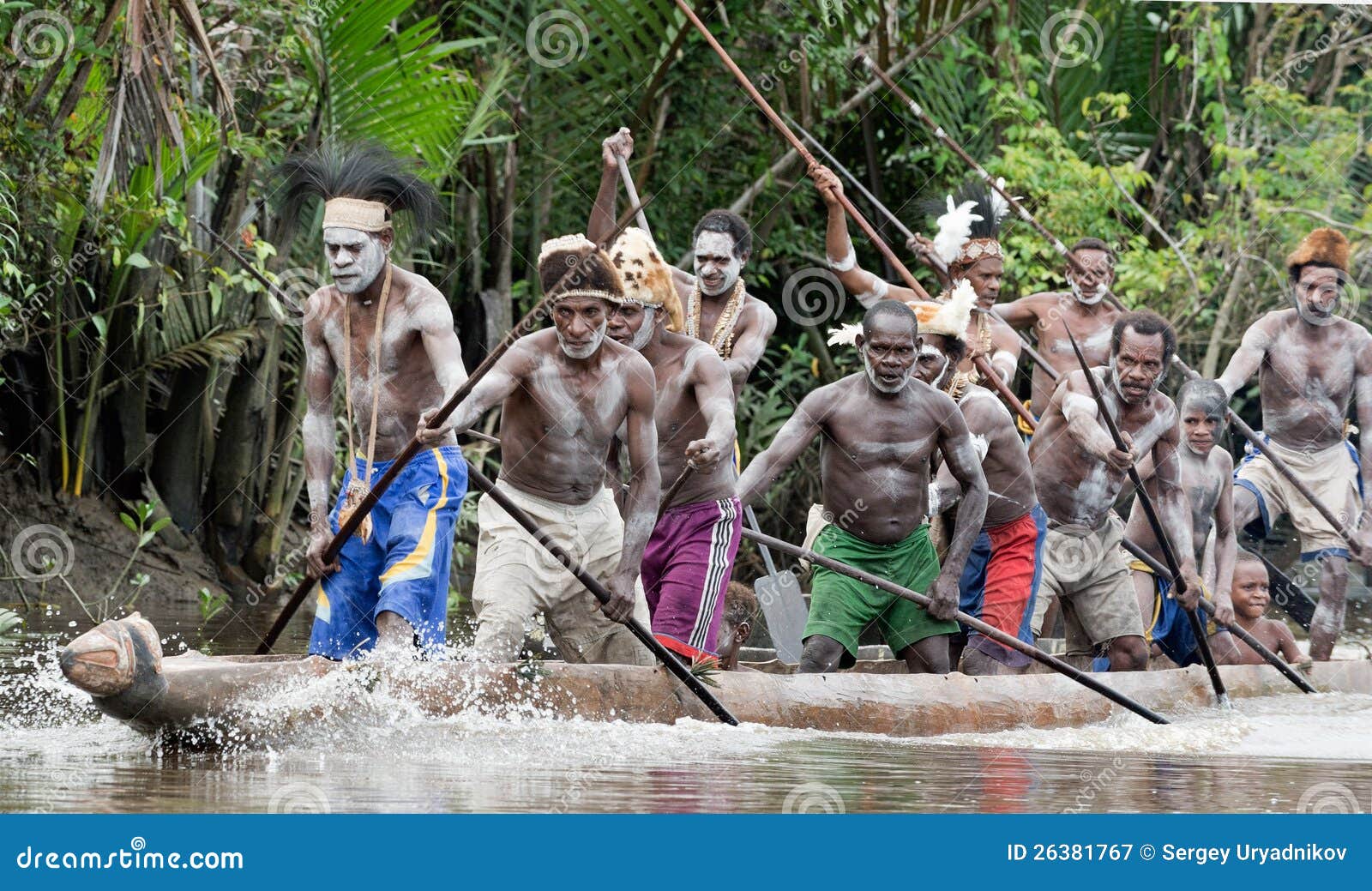 asmat men paddling in their dugout canoe editorial