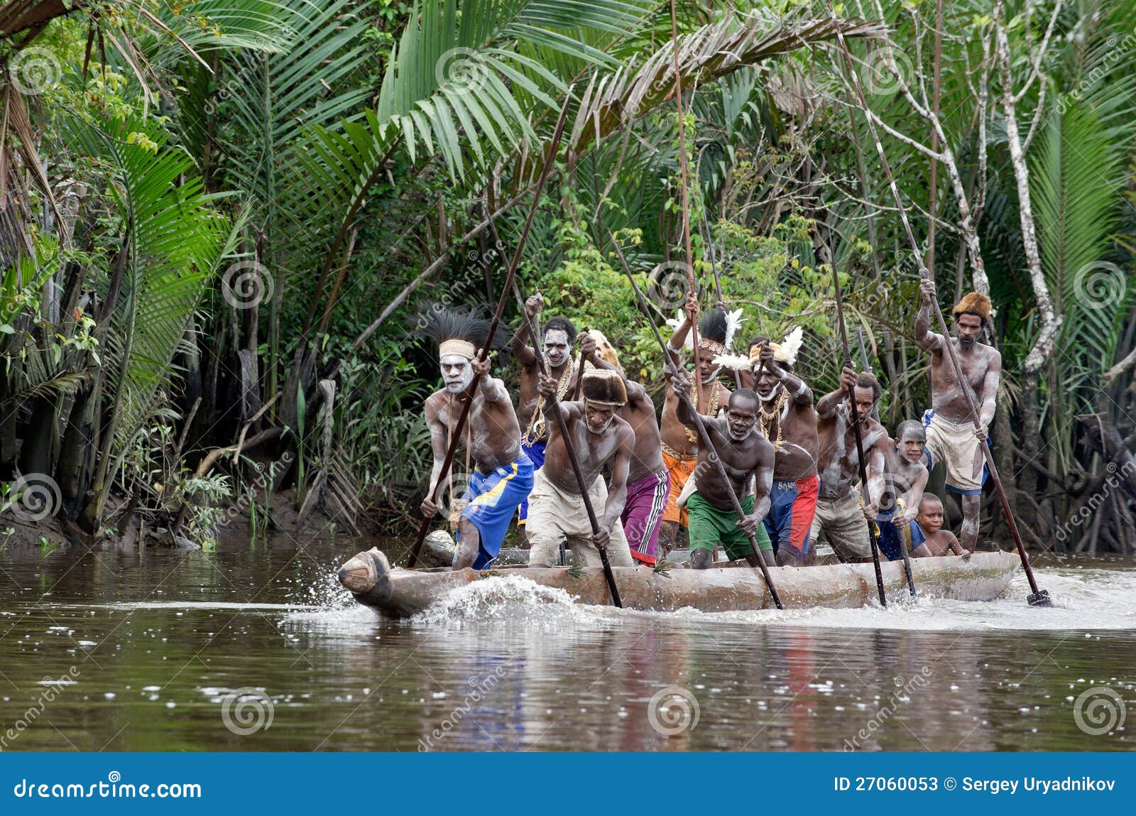 asmat men paddling in their dugout canoe editorial stock