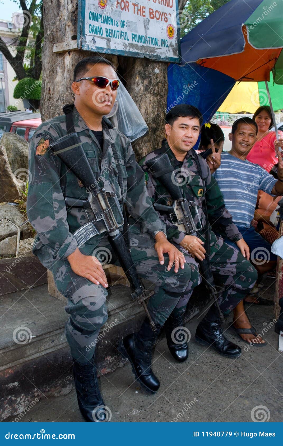 Assediamento militare della città di Mindanao. Due soldati molto muniti del NPA (esercito filippino nazionale) stanno custodicendo l'ambiente municipio (Mindanao, Filippine) della città di Davao e dei civili sul servizio di via là durante l'una delle baldorie del bombardamento del terrorista nella città. Quadrato del municipio della città di Davao, Mindanao, Filippine, il 23 maggio 2008 a 2pm.