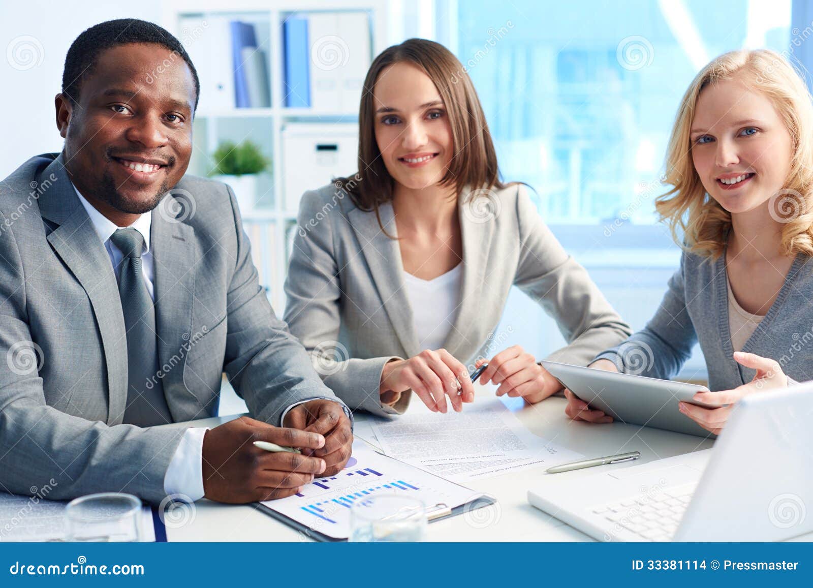 Associés réussis. Image de trois associés regardant l'appareil-photo avec des sourires dans le bureau