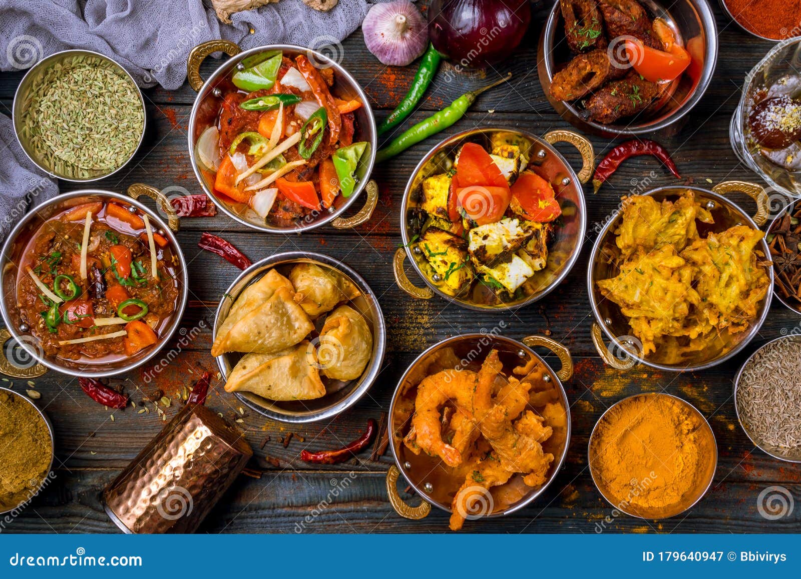 assorted indian food set on wooden background. dishes and appetisers of indeed cuisine, rice, lentils, paneer, samosa, spices, mas