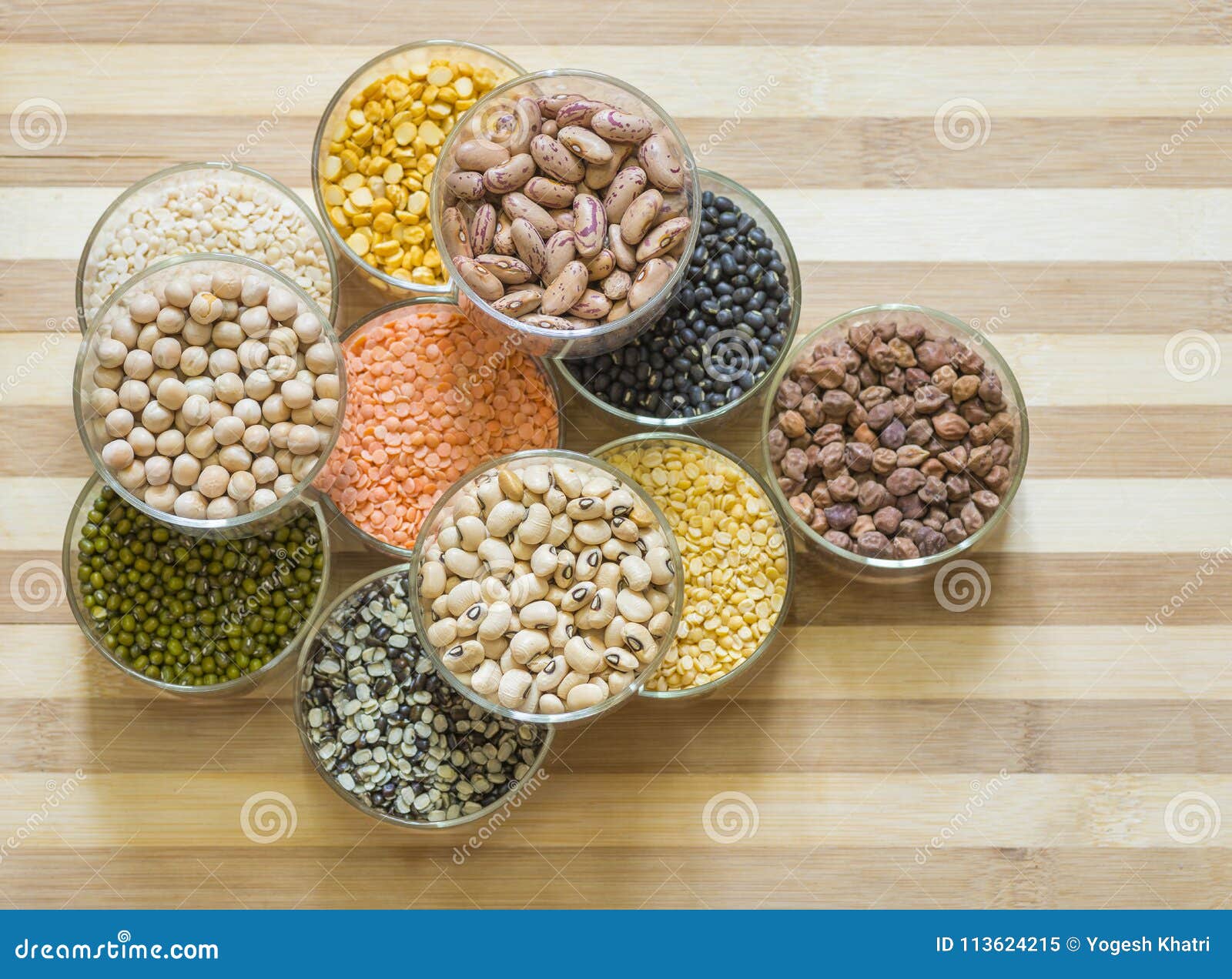 assorted lentils and legumes in glass bowls, ona chopping board