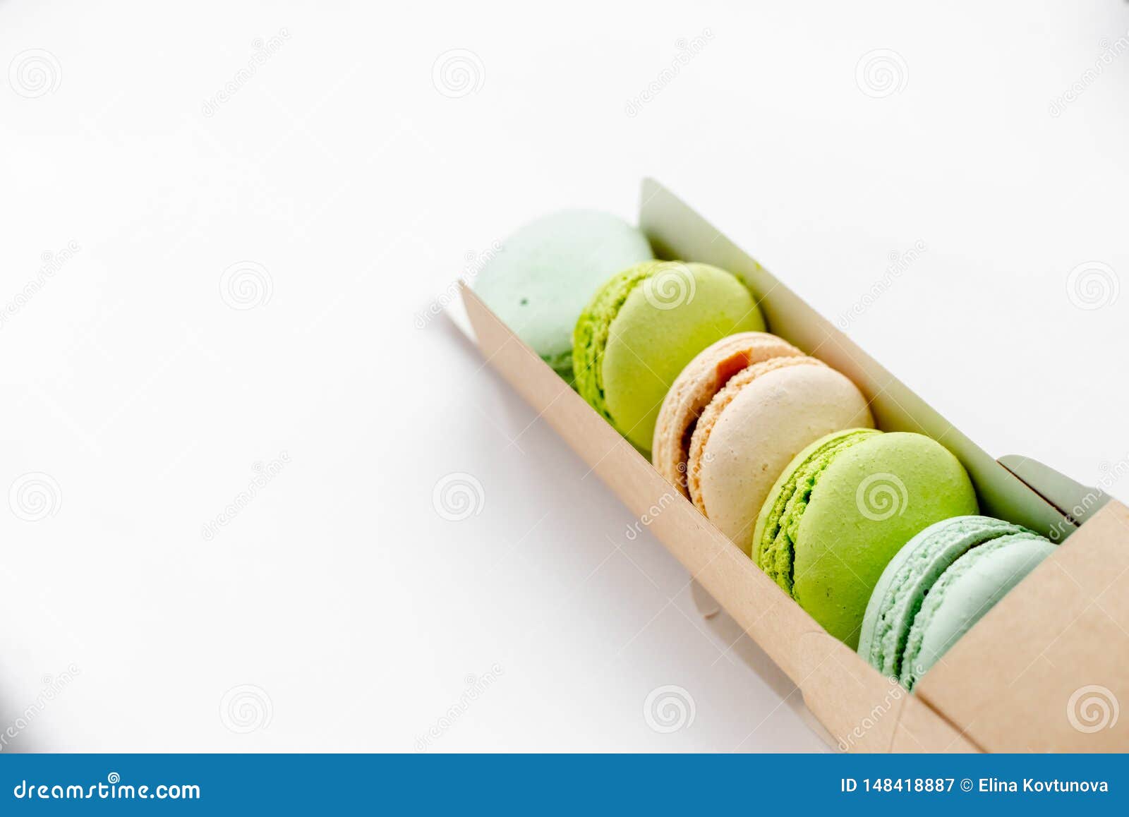 assorted macaroons in craft paper box flat lay.white table background. top view copyspace horizontal