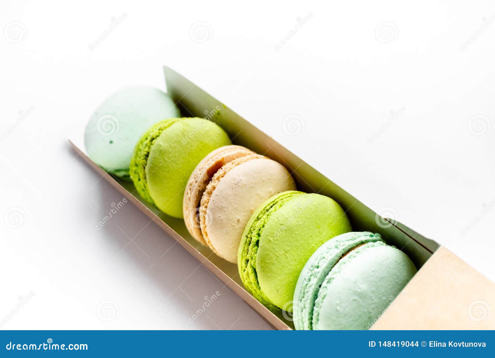 Assorted Macaroons In Craft Paper Box Flat Lay.white Table
