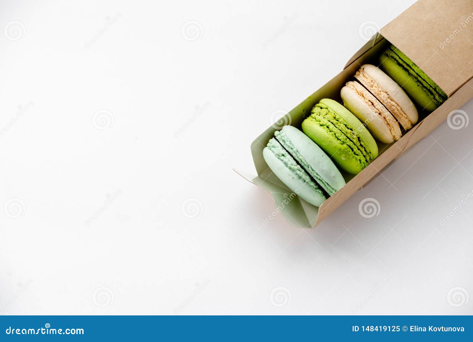 assorted macaroons in craft paper box flat lay.white table background. top view copyspace horizontal