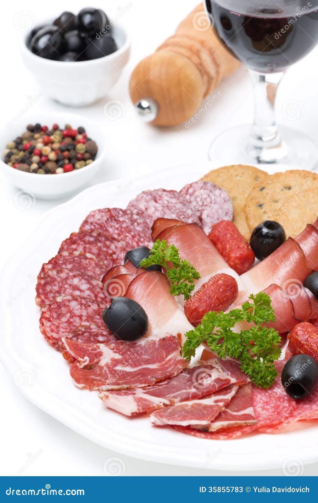 Assorted meat delicacies on a plate and a glass of wine, close-up