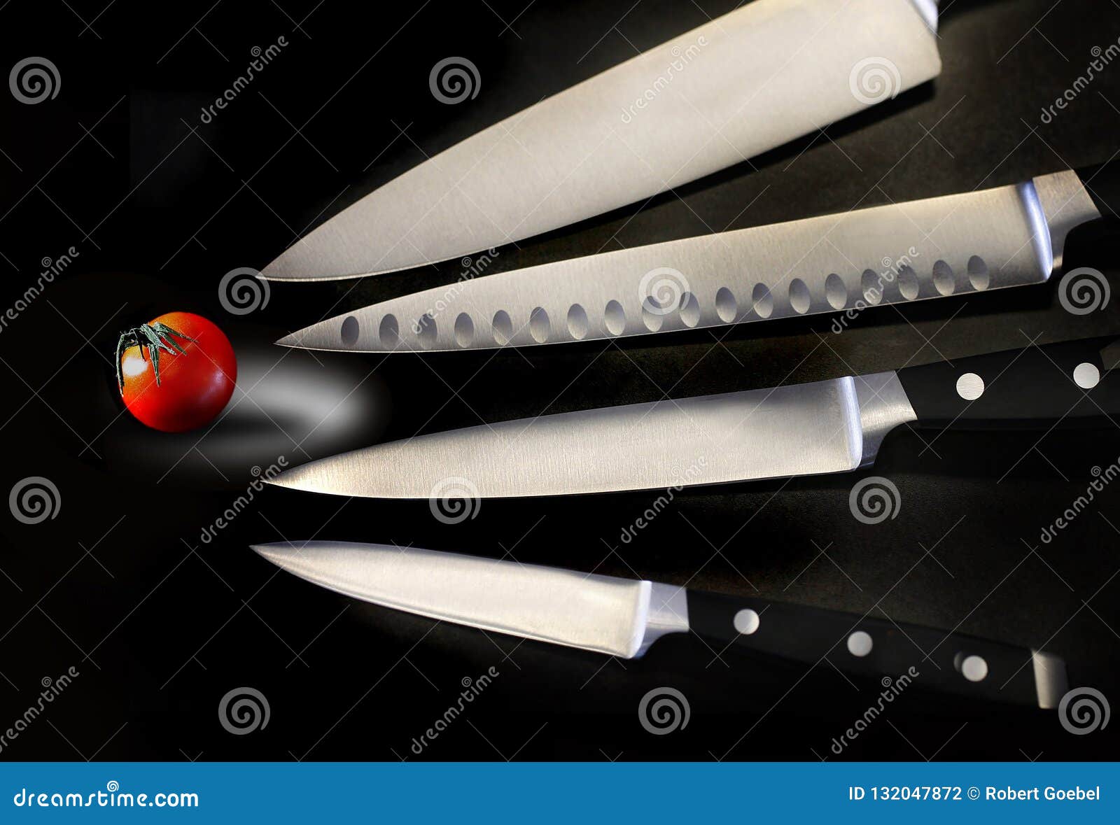 Assorted Sharp and Shiny Kitchen Knives are Seen with a Small Tomato in