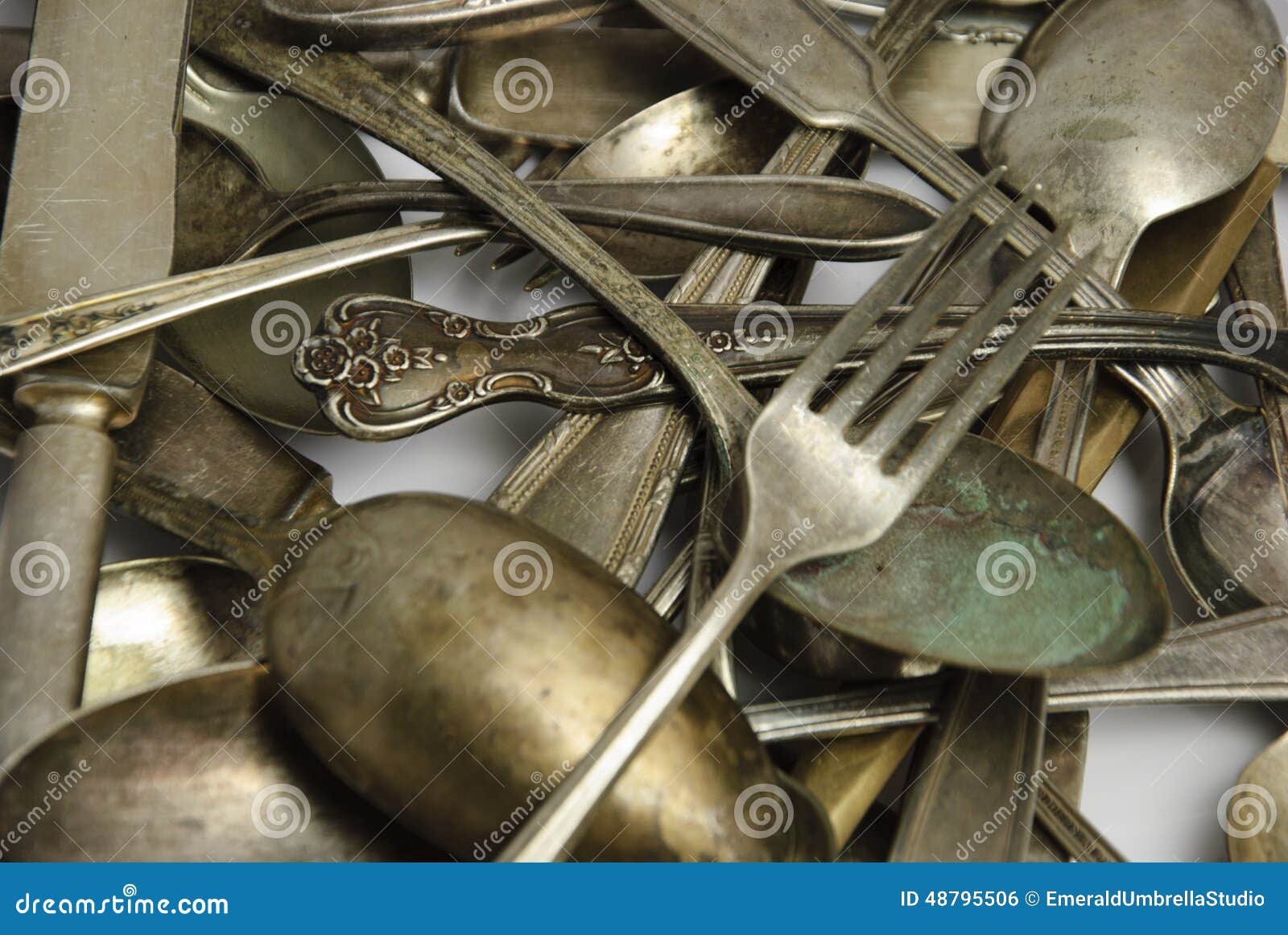 assorted tarnished antique flatware on white