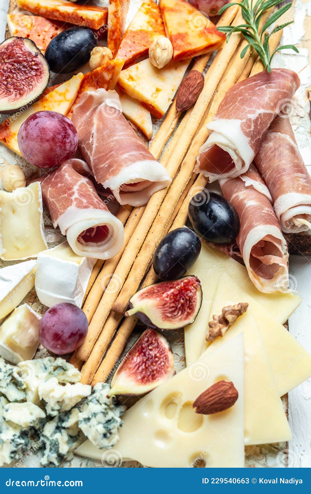 Assortment of Cheese with Prosciutto, Honey, Nuts and Grape on Cutting