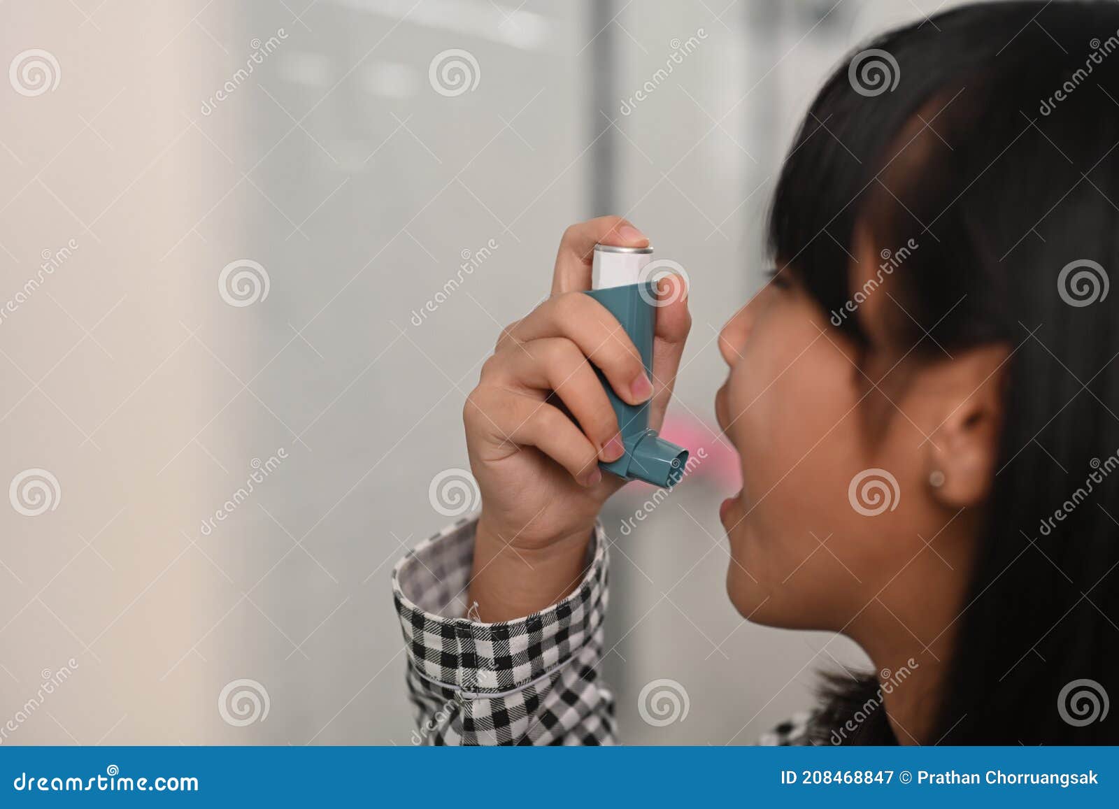 asthmatic young girl using an asthma inhaler while suffering from asthma in toilet.