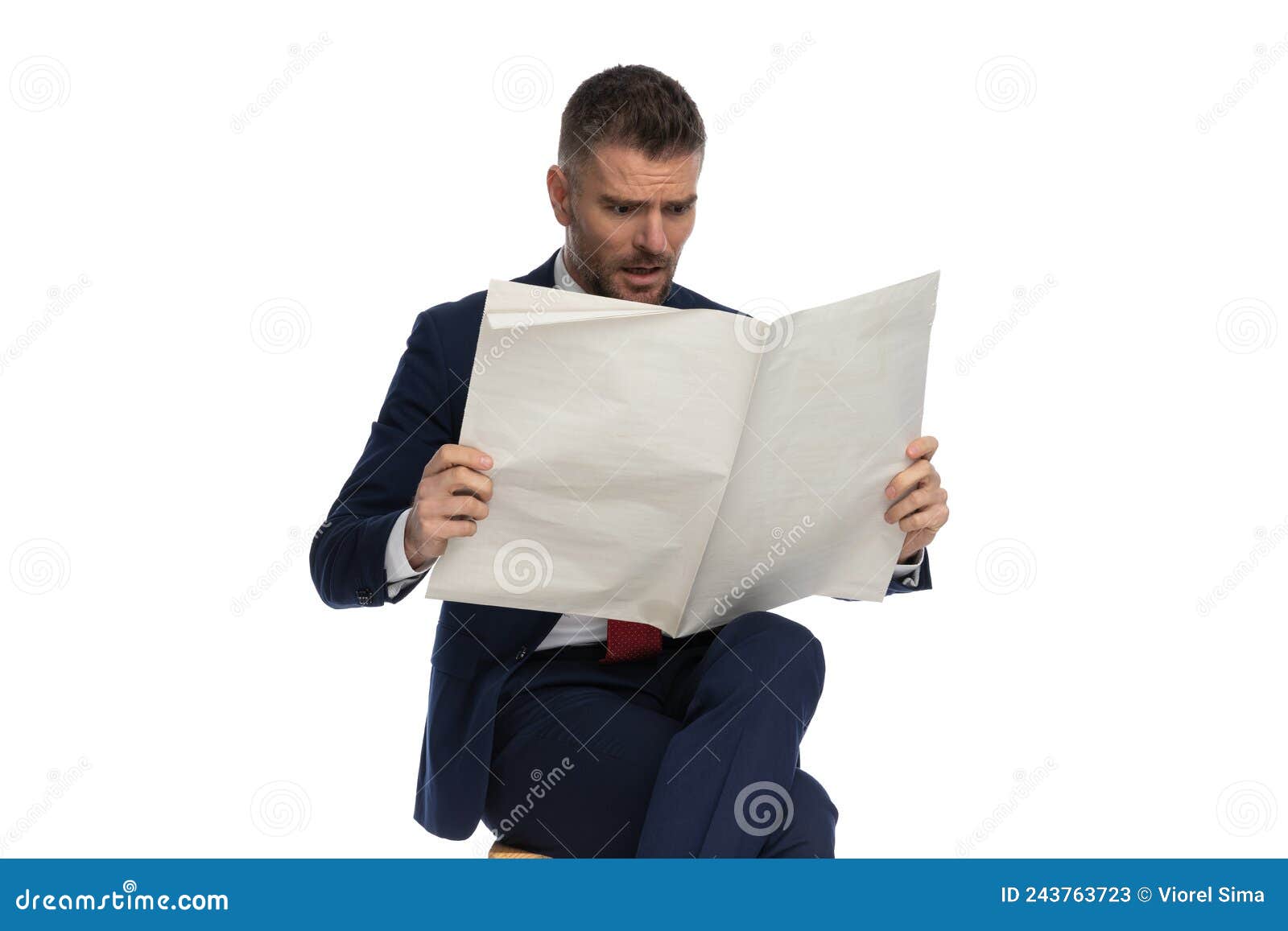 astounded man in his 40s reading newspaper and being shocked