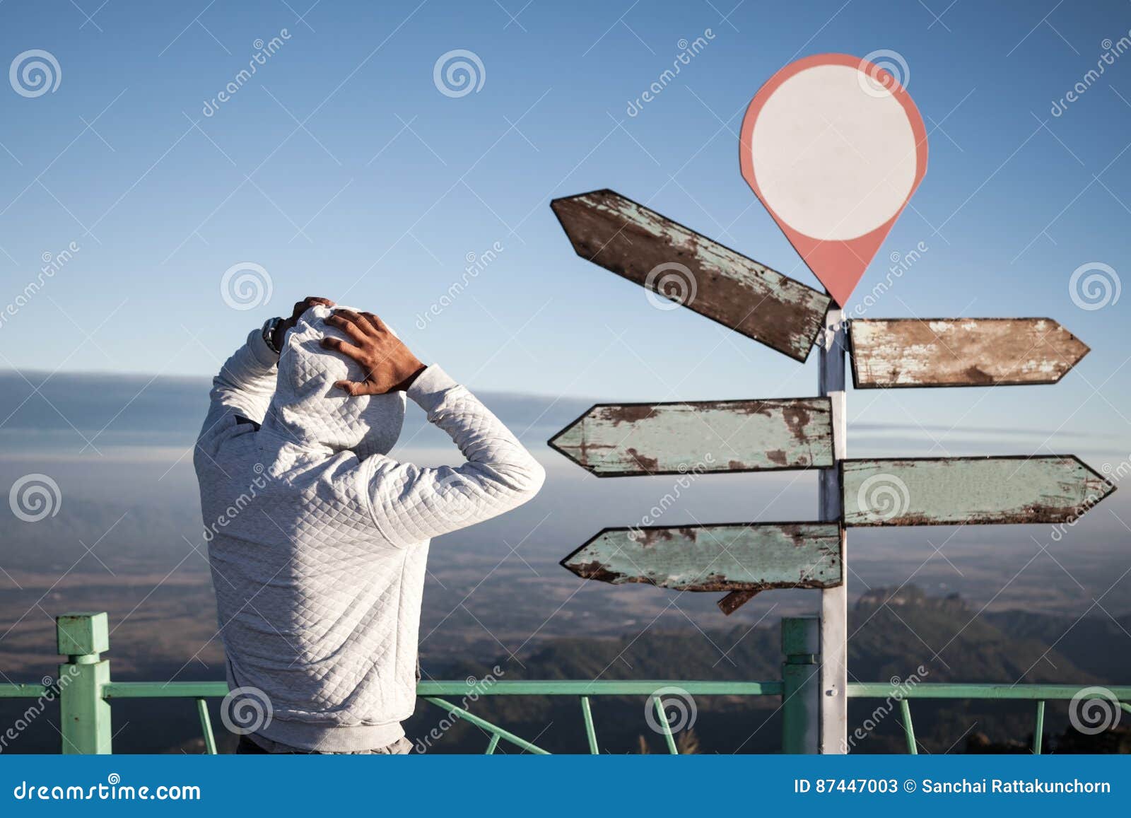 astray man in doubt standing and confused in front of blank guidepost.