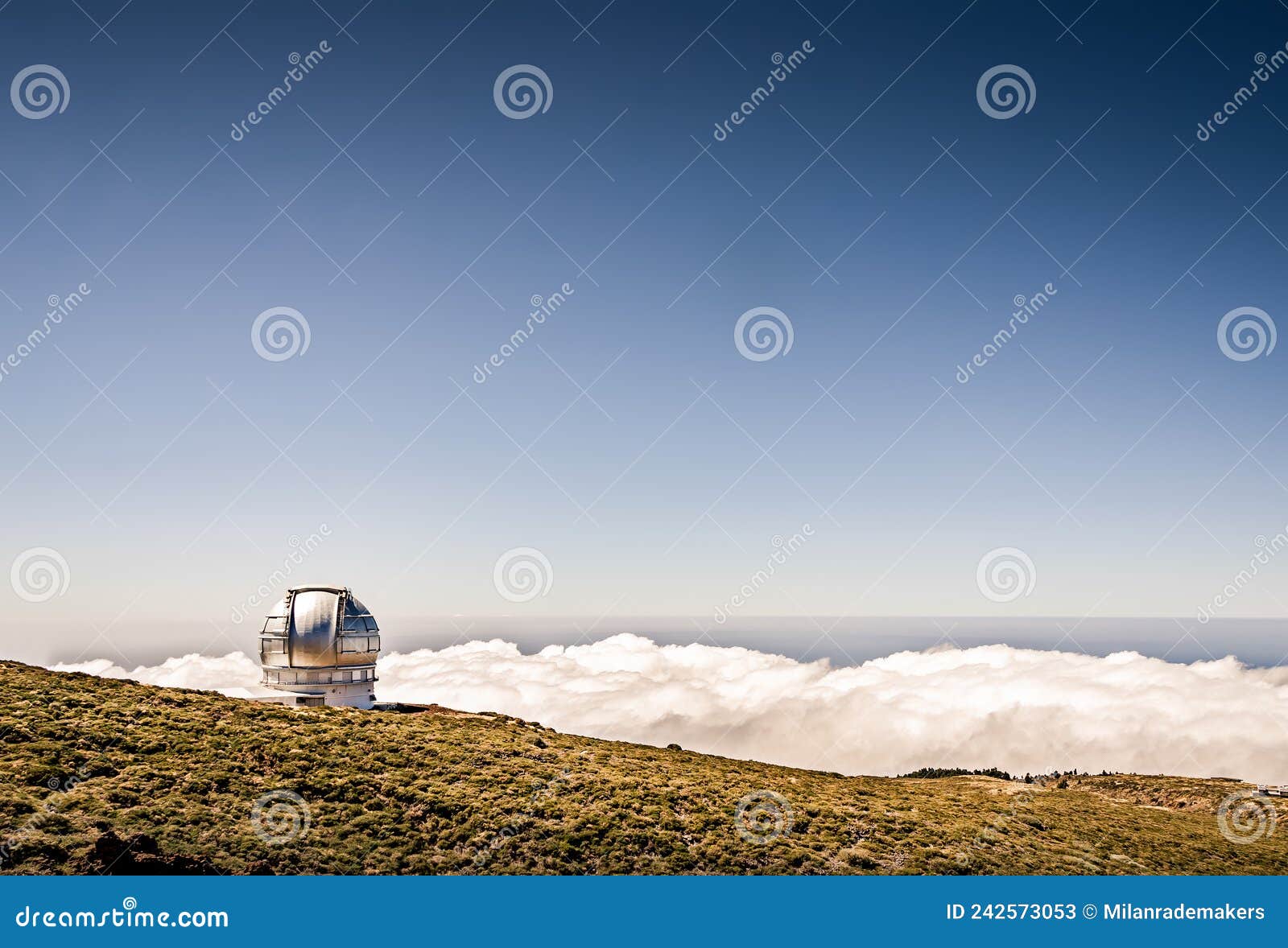 astronomy observatory on a mountain above the clouds with blue sky. gran telescopio canarias. telescope dome with beautiful