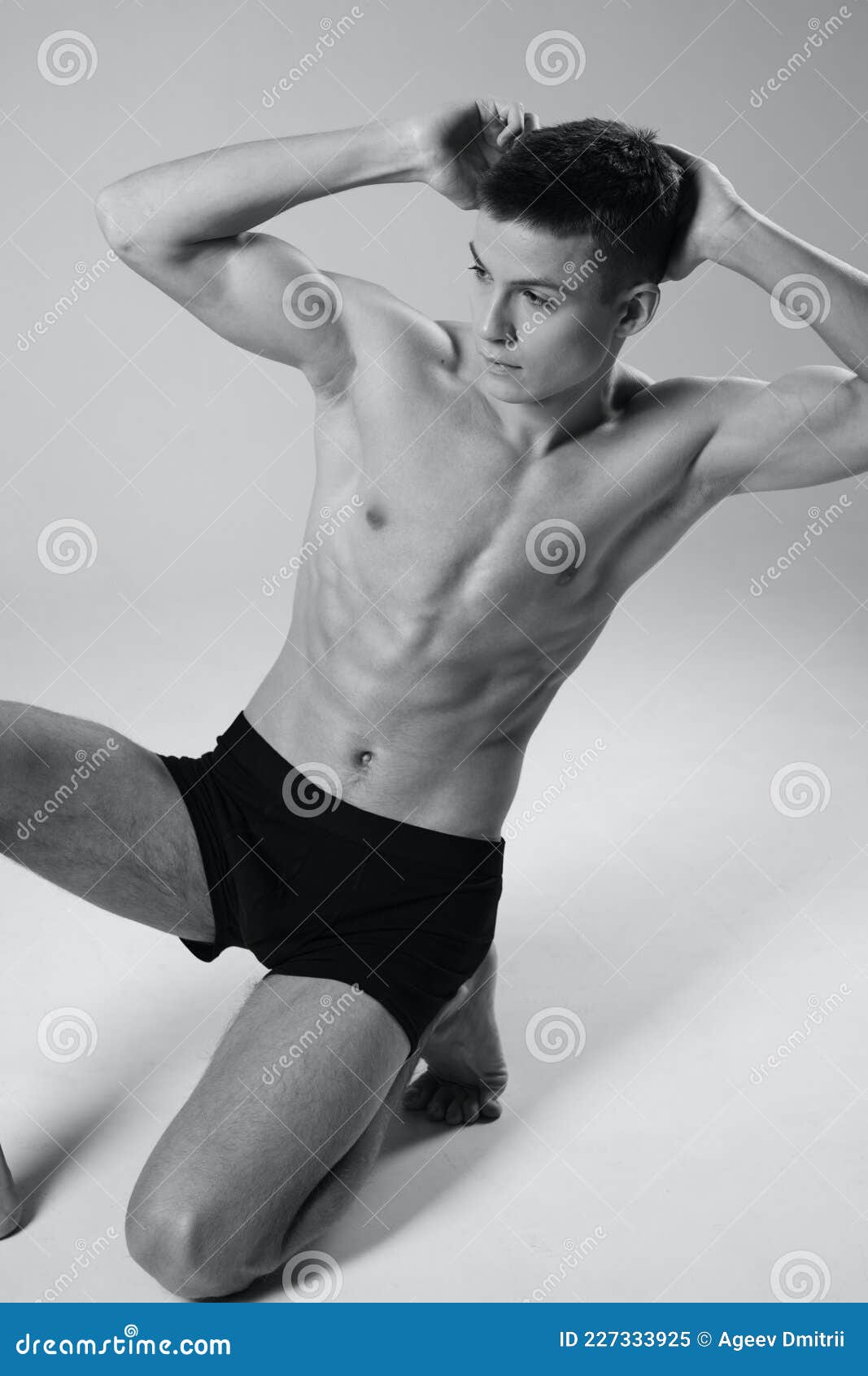 Athlete Sitting On The Floor Indoors In Shorts And Naked Torso Black