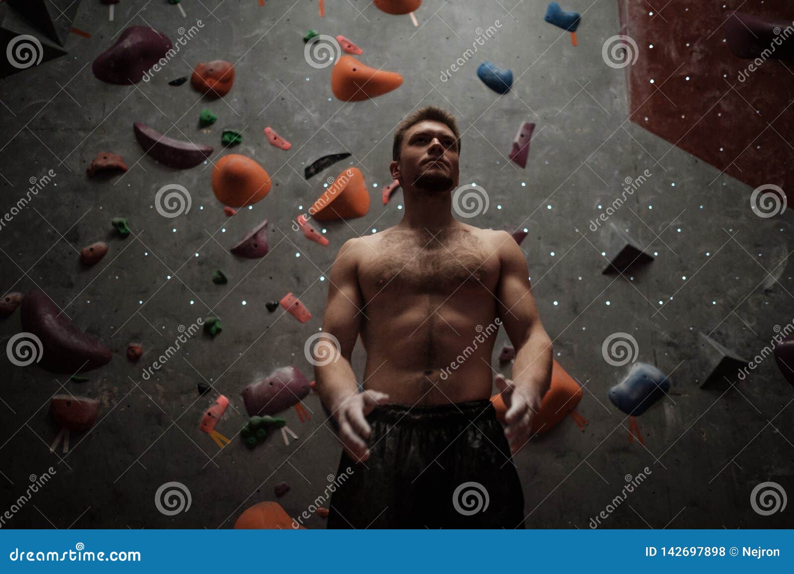 Athletic Man Using Chalk before Climbing in a Bouldering Gym Stock