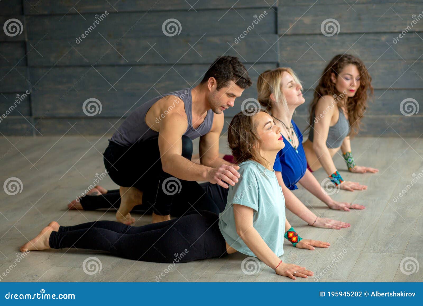 Male Yoga Instructor Teaching Yoga To Three Young Women Stock Photo