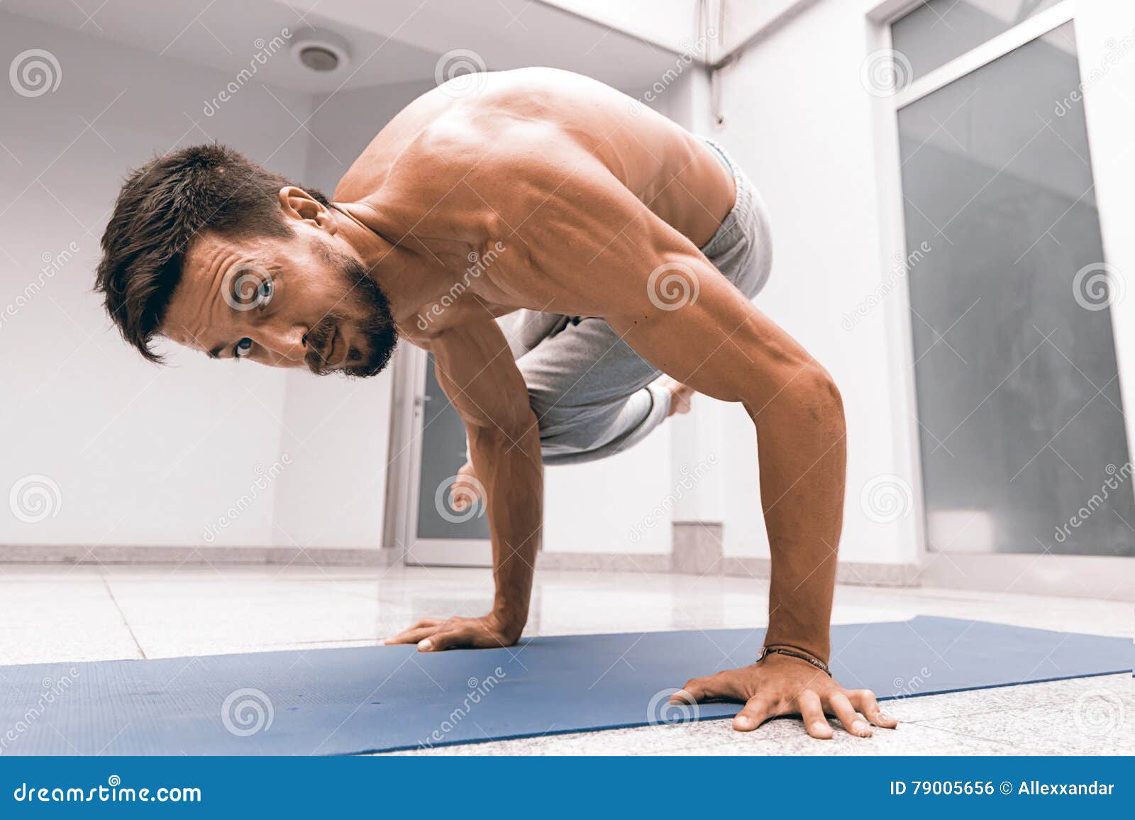 Athletic Strong Man Practicing Difficult Yoga Pose. Stock Photo