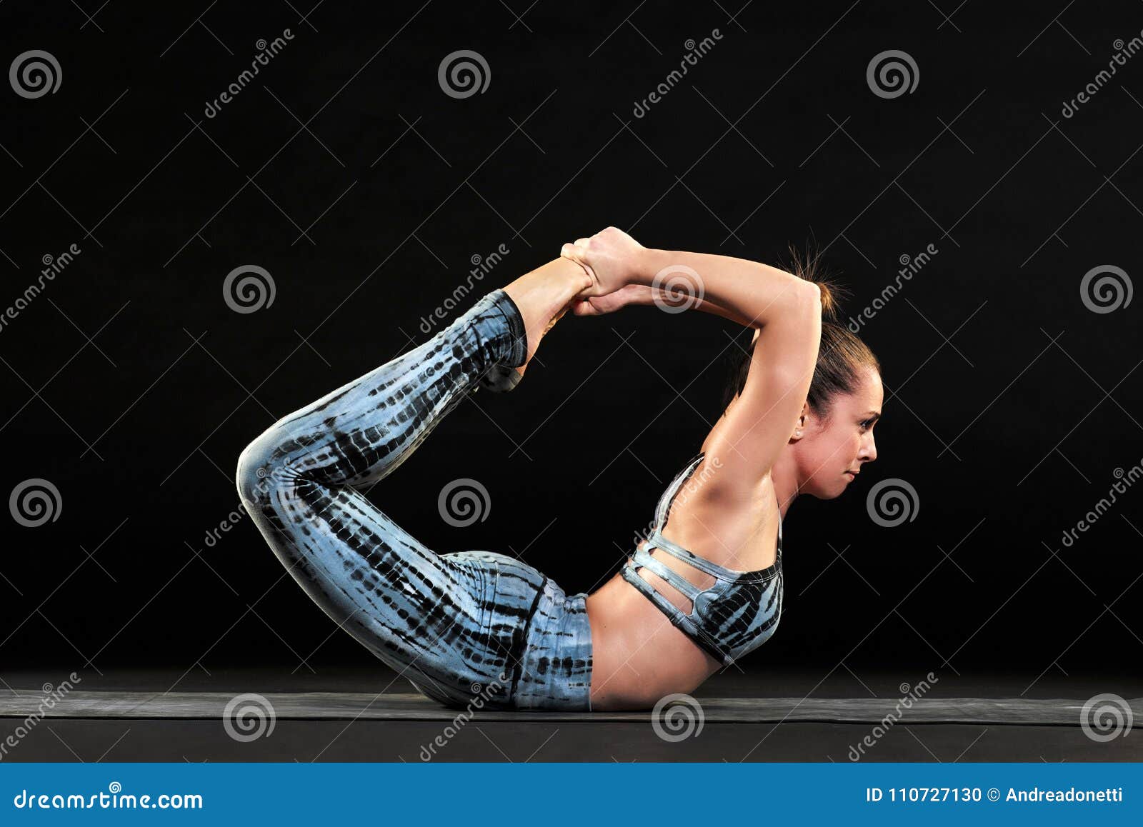Barefooted Flexible Woman Stretching Body In Standing Bow Pose While  Practicing Yoga At Home