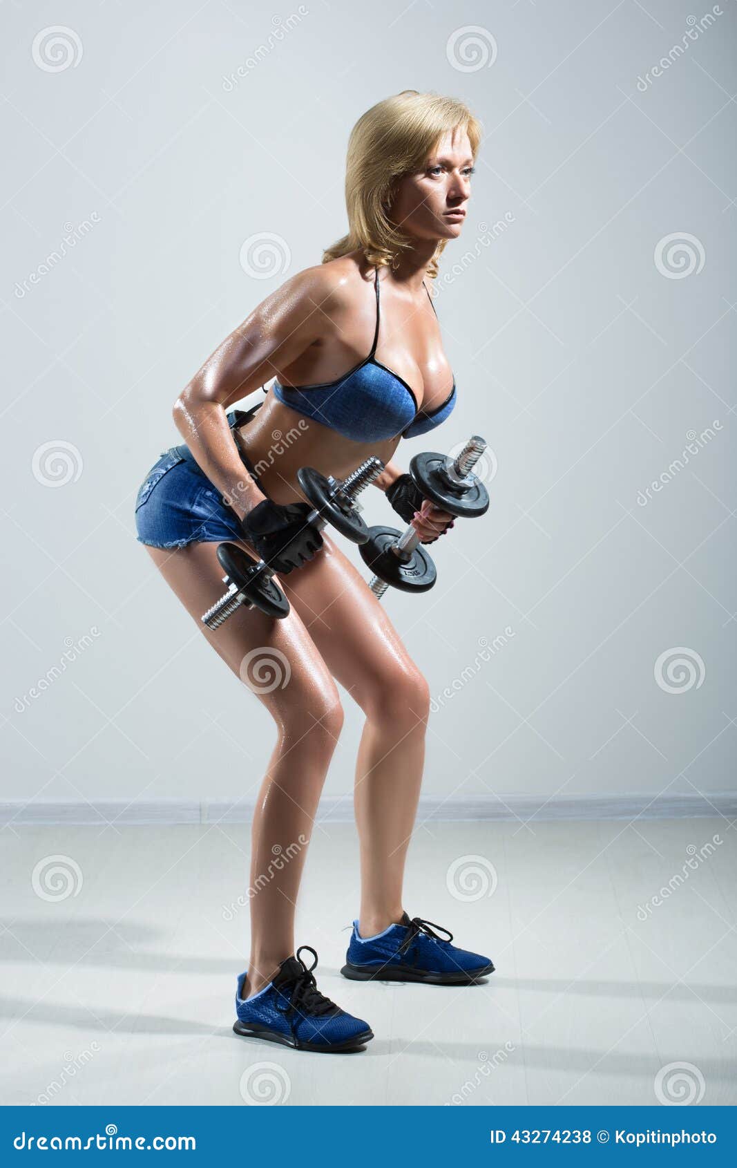 Athletic Woman Pumping Up Muscules with Dumbbells Stock Photo