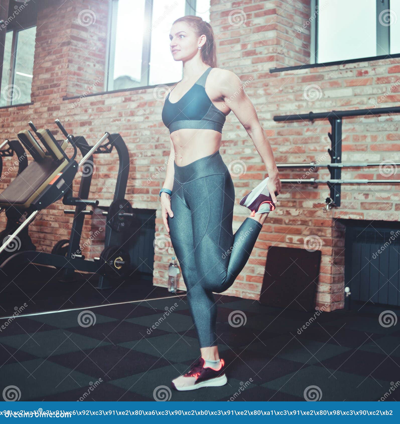 Young athletic woman in sportswear posing in studio against black  background. Ideal female sports figure. Fitness girl with perfect sculpted  muscular and tight body. Stock Photo