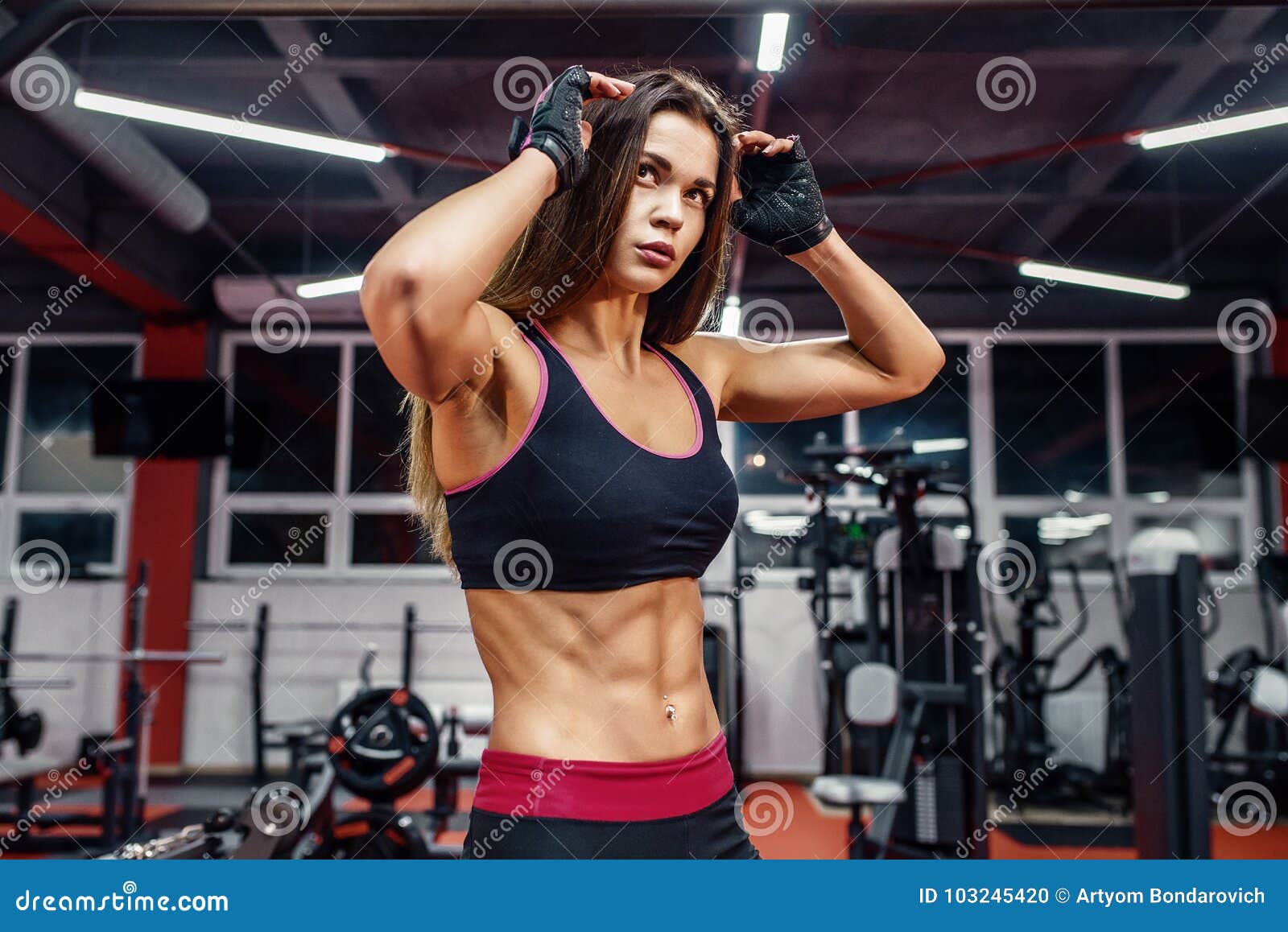 athletic young woman showing muscles after workout in gym.