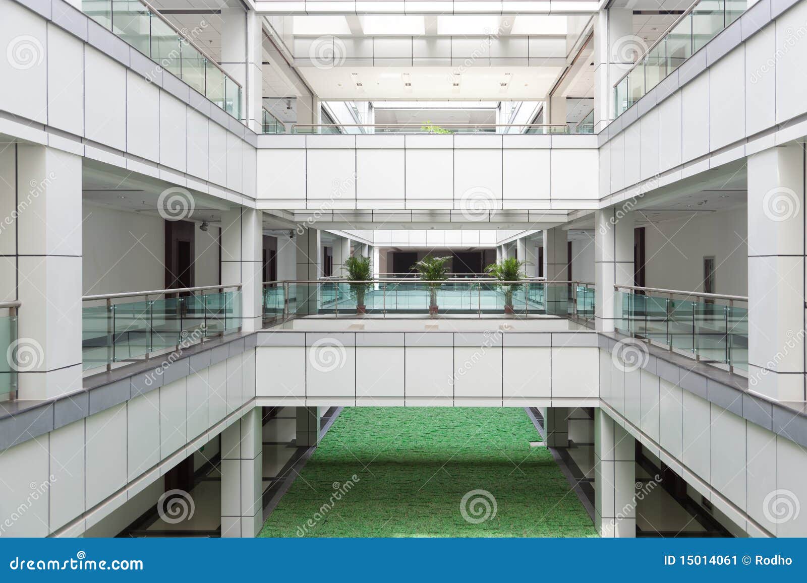 Atrium in een bureaugebouw. Het open atrium met het onder ogen zien van gangen en de mens maakten gazonvloer in een bureaugebouw