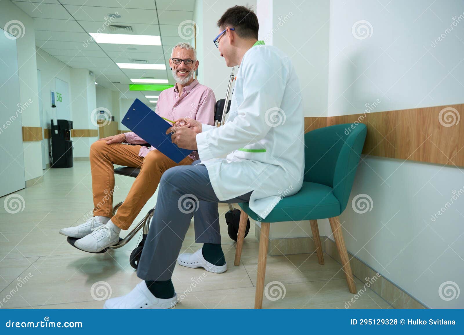 Attending Physician In A Medical Gown Conducts Questionnaire On Patient attending-physician-in-a-medical-gown-conducts-questionnaire-on-patient