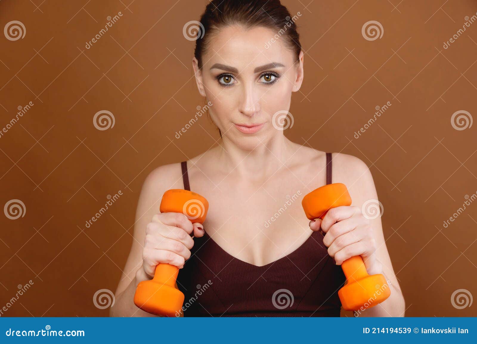 Attractive Athlete Positive Caucasian Woman Is Engaged In Fitness With Orange Dumbbells The