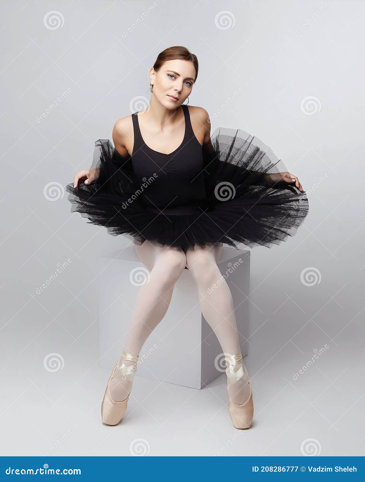 Attractive Ballerina Poses Gracefully while Sitting on a Cube. Photo Shoot in the Studio on a White Background Stock Image - Image of dance, 208286777