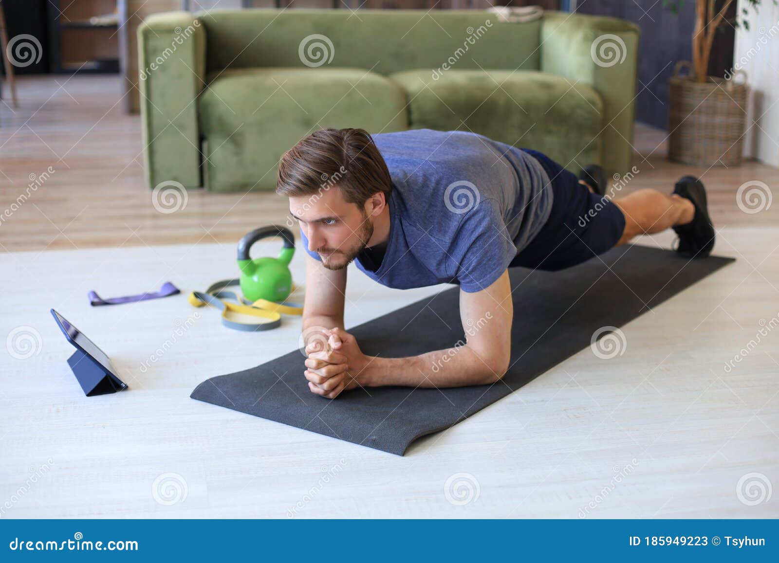 attractive beared man doing plank exercise at home during quarantine. fitness is the key to health