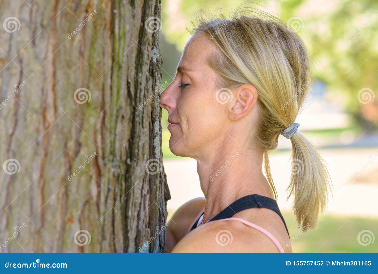 attractive blond female nature lover hugging tree