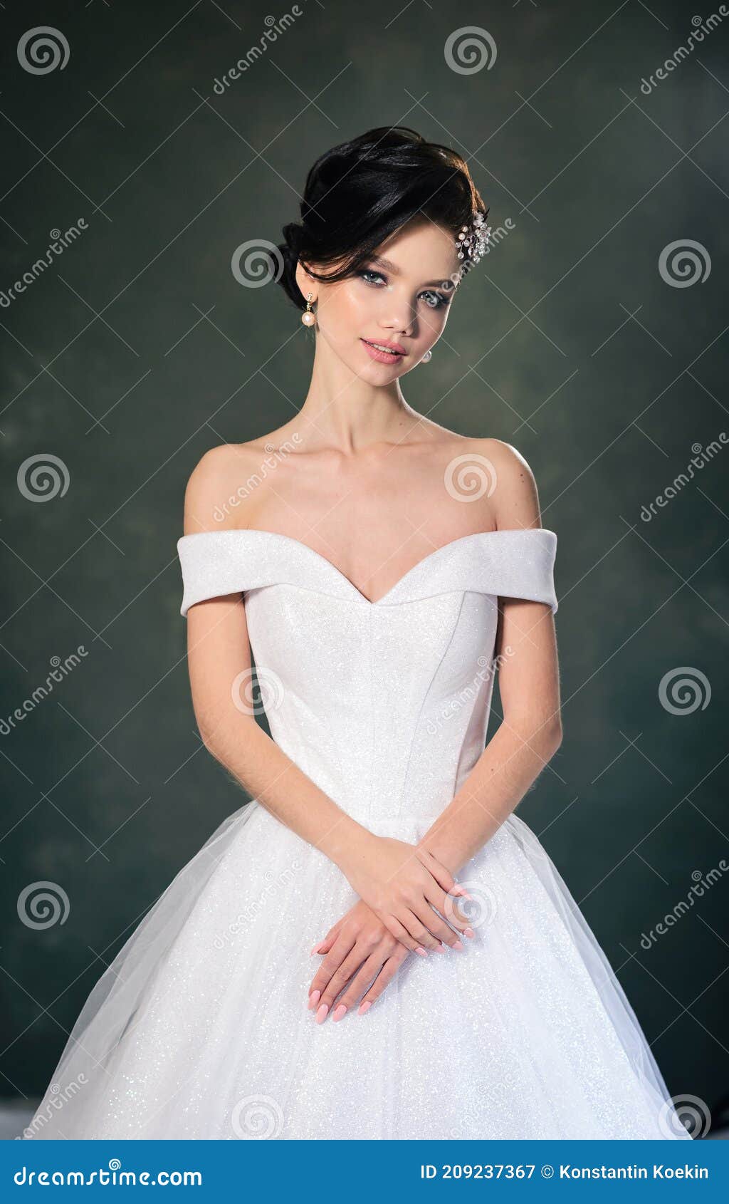 Bride in lingerie dancing with her wedding dress. White boudoir dress.  Morning preparations indoors. Luxury bride with hairstyle and makeup in a  hotel or apartment. Woman in white night gown and veil