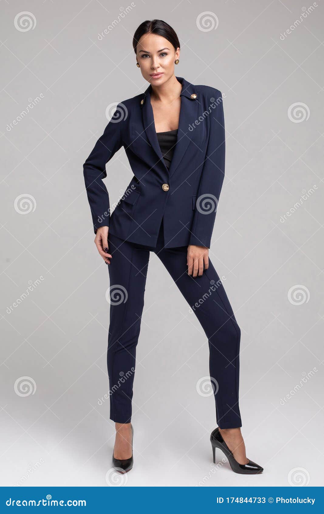 Businesswoman in blue suit and black high heels is sitting on a top of a  white banner and smiling. Full length studio shot Stock Photo - Alamy