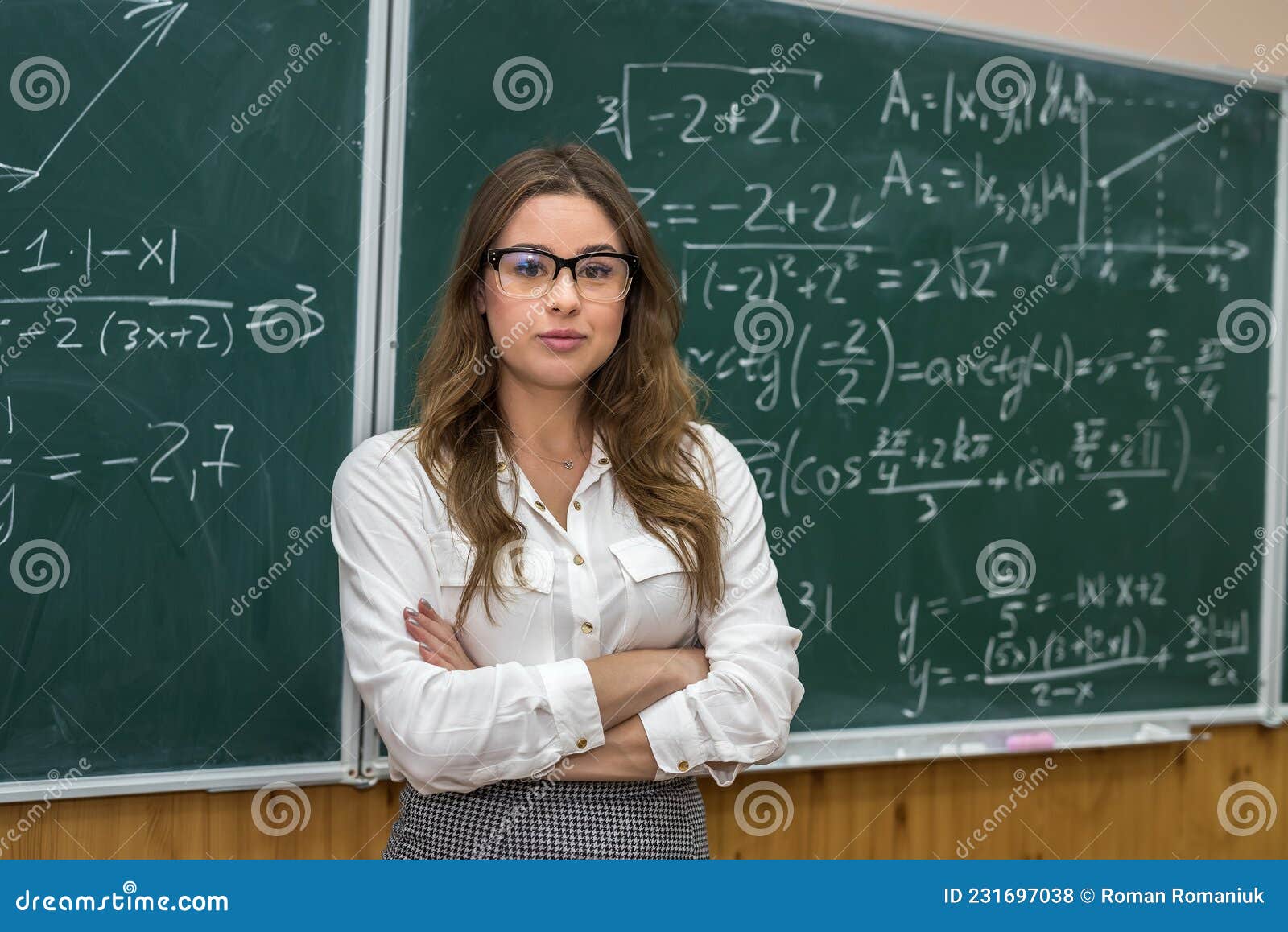 Attractive Female Teacher In Glasses Near Blackboard With Math