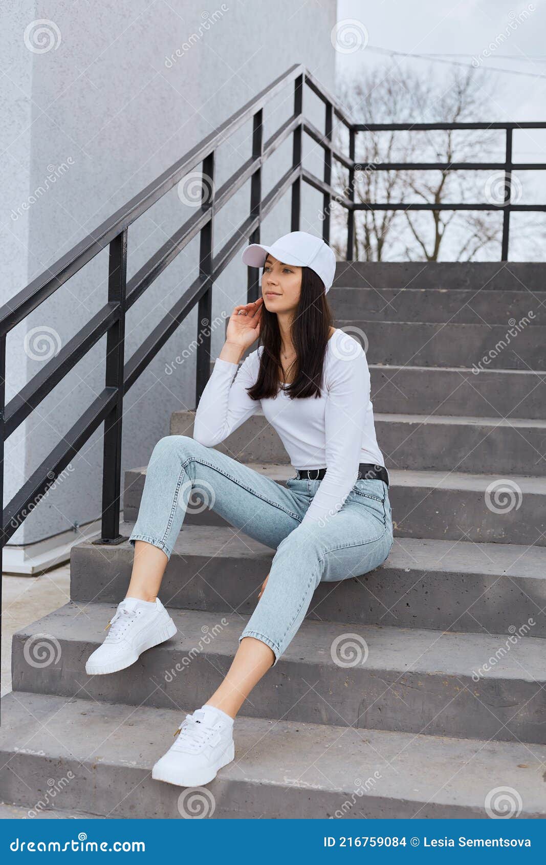 Attractive Female Wearing Stylish Jeans, White Shirt and Baseball Cap,  Sitting on Stairs and Looking Away with Thoughtful Stock Photo - Image of  pensive, happy: 216759084