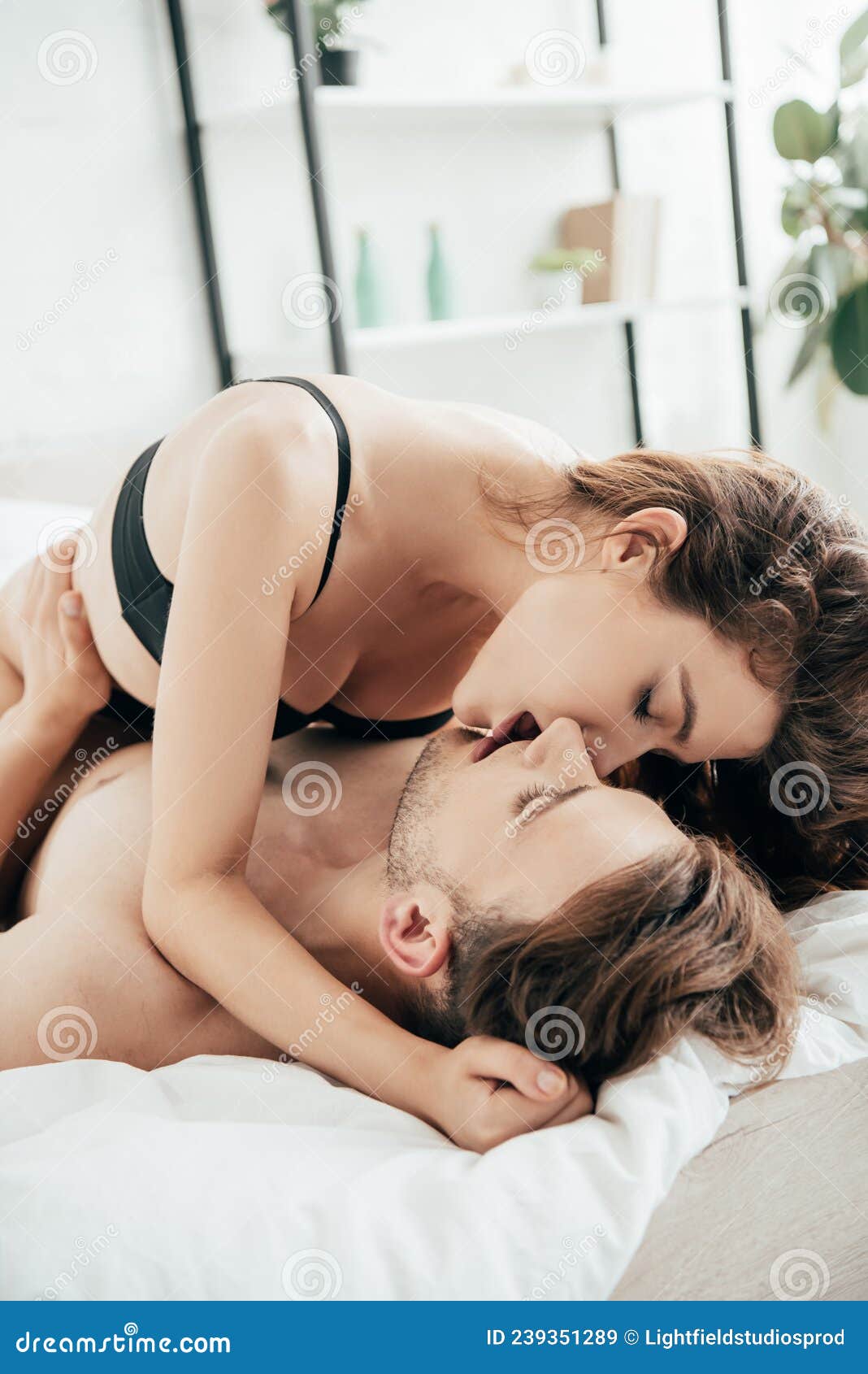 Lovers in Underwear Hugging and Kissing in Bedroom Stock Photo