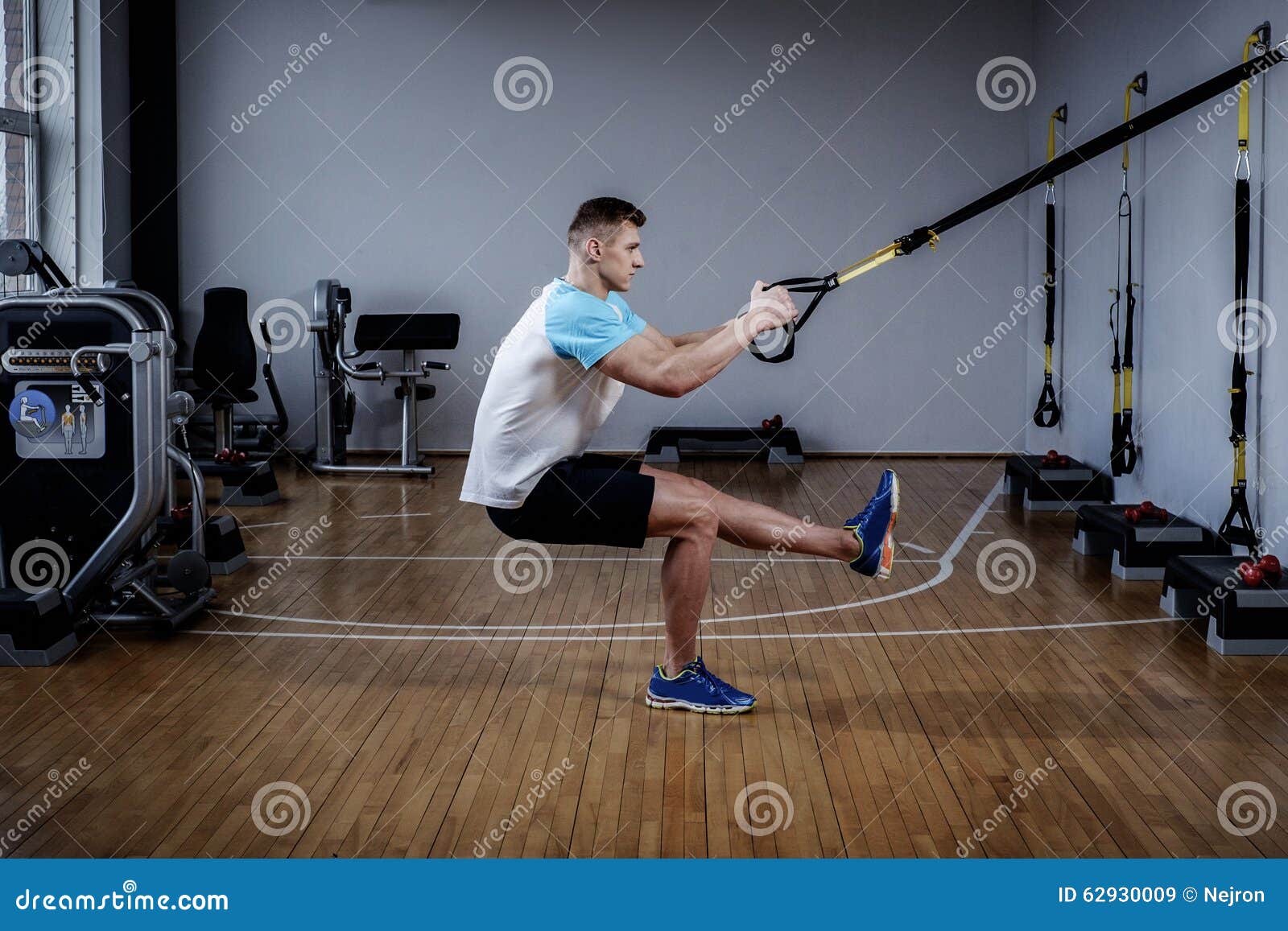 Attractive Man during Workout with Suspension Straps in the Gym Stock