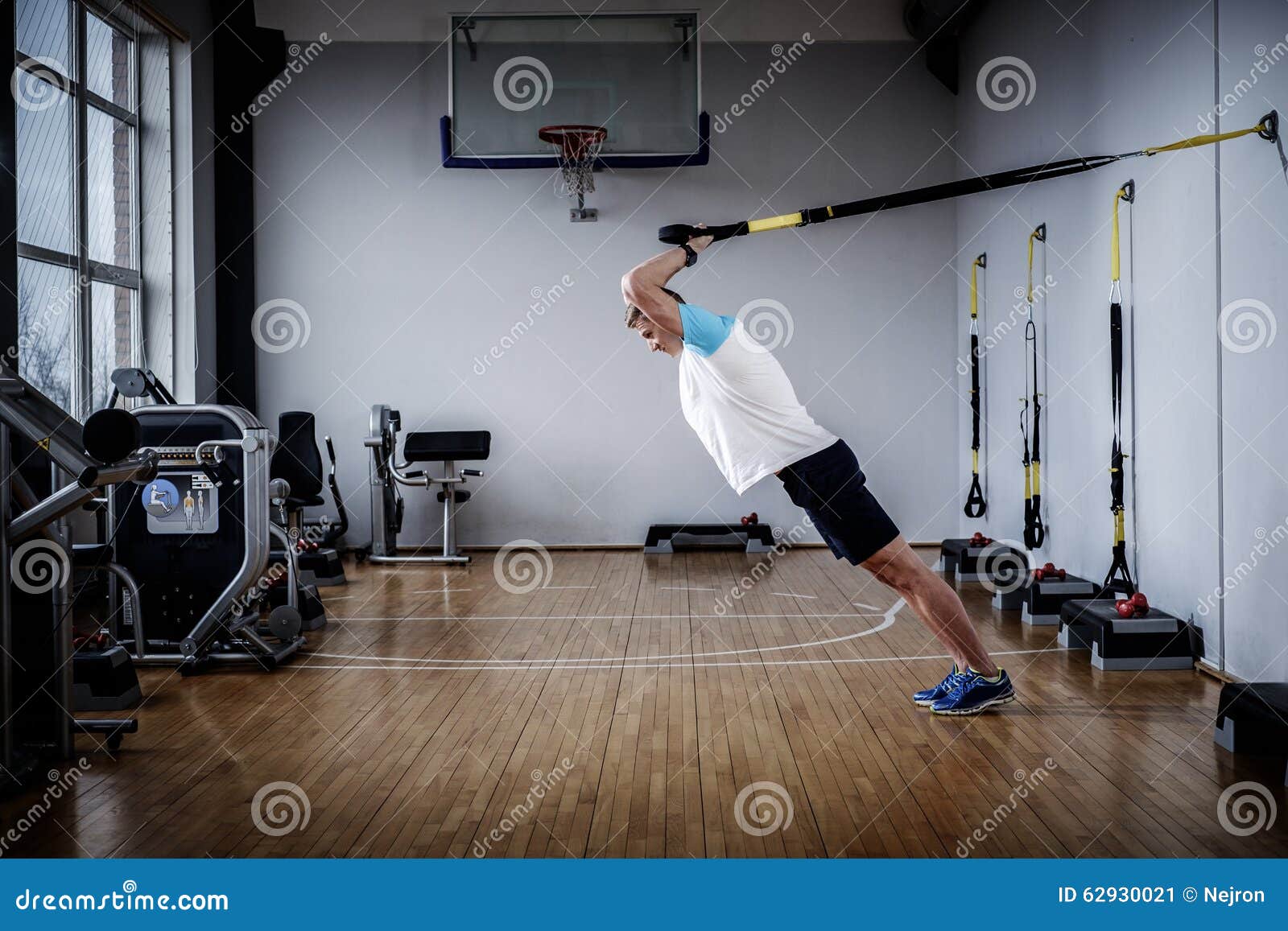 Attractive Man during Workout with Suspension Straps in the Gym Stock