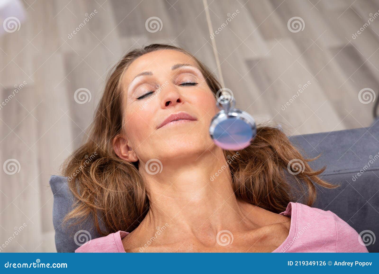 woman being hypnotized while lying on sofa