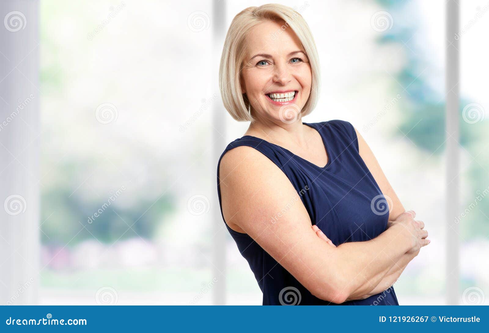 attractive middle aged woman with a beautiful smile near the window.
