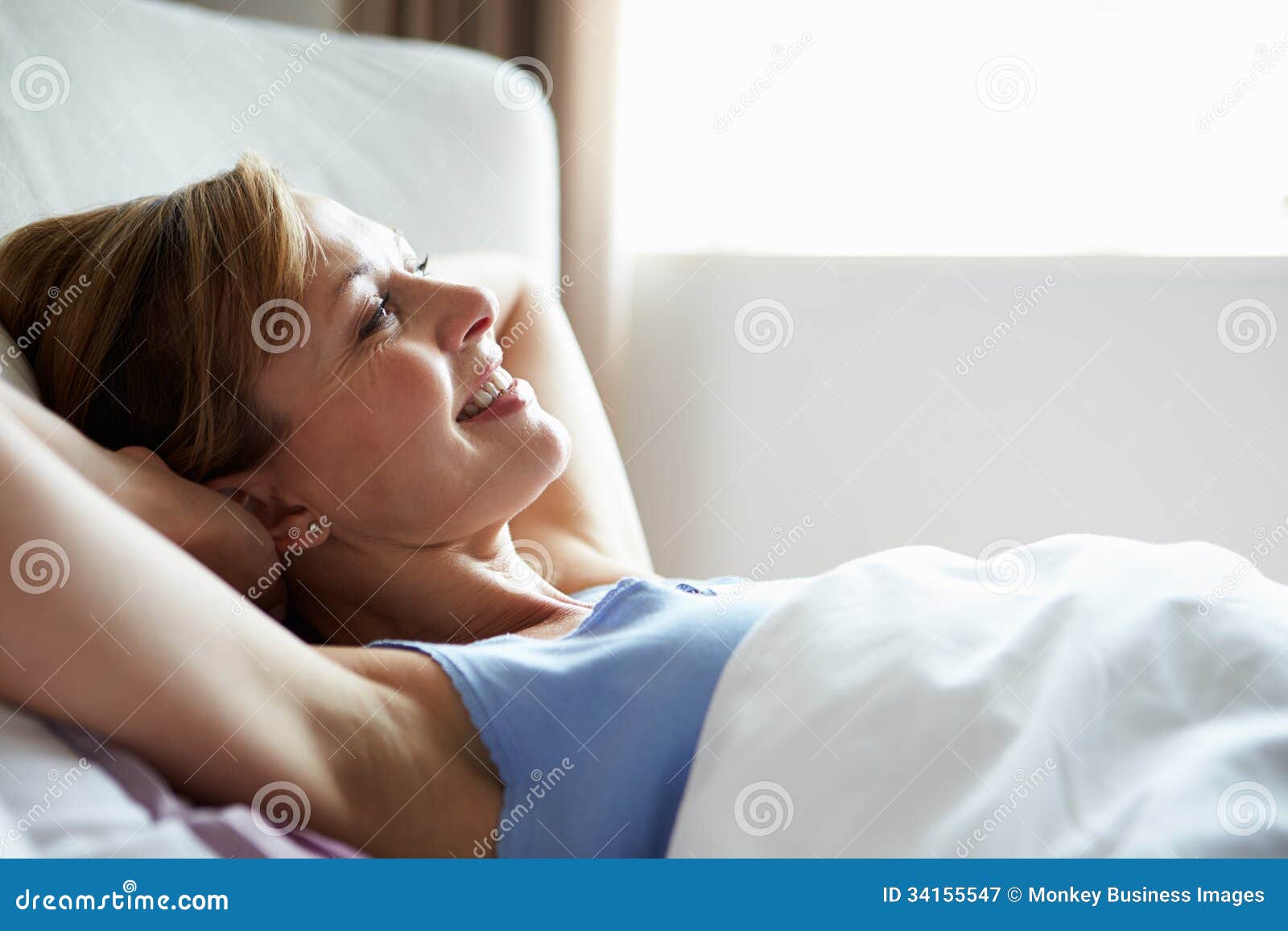 attractive middle aged woman waking up in bed
