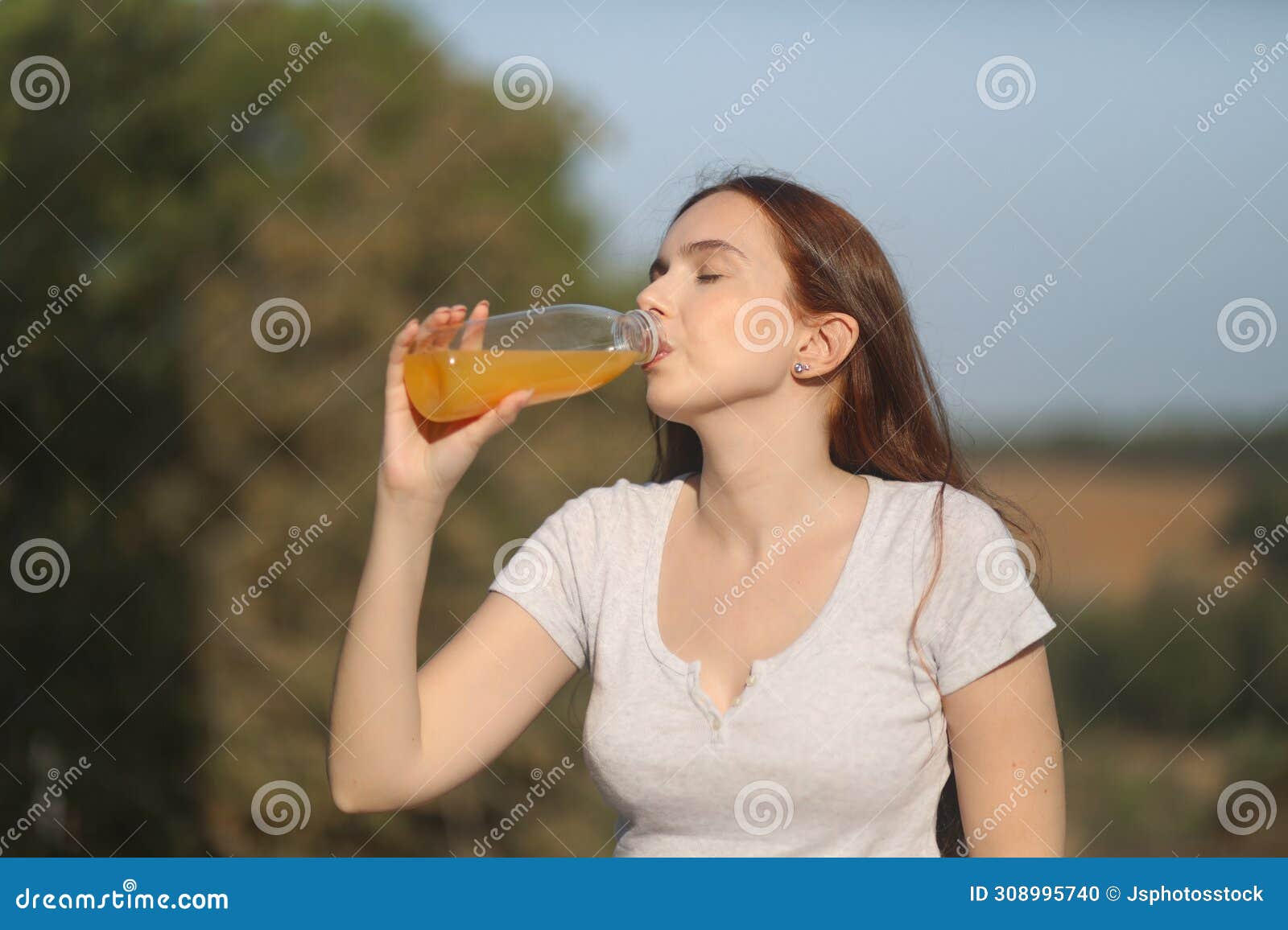 young woman drinks orange juice on a sunny summer day