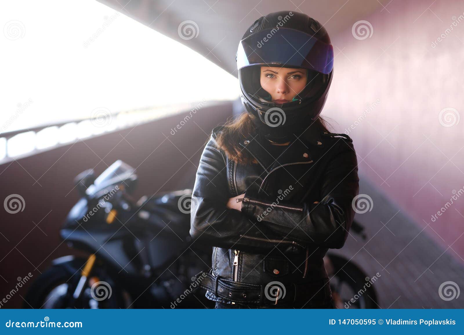 attractive serious woman is standing next to her motobike crossing hands