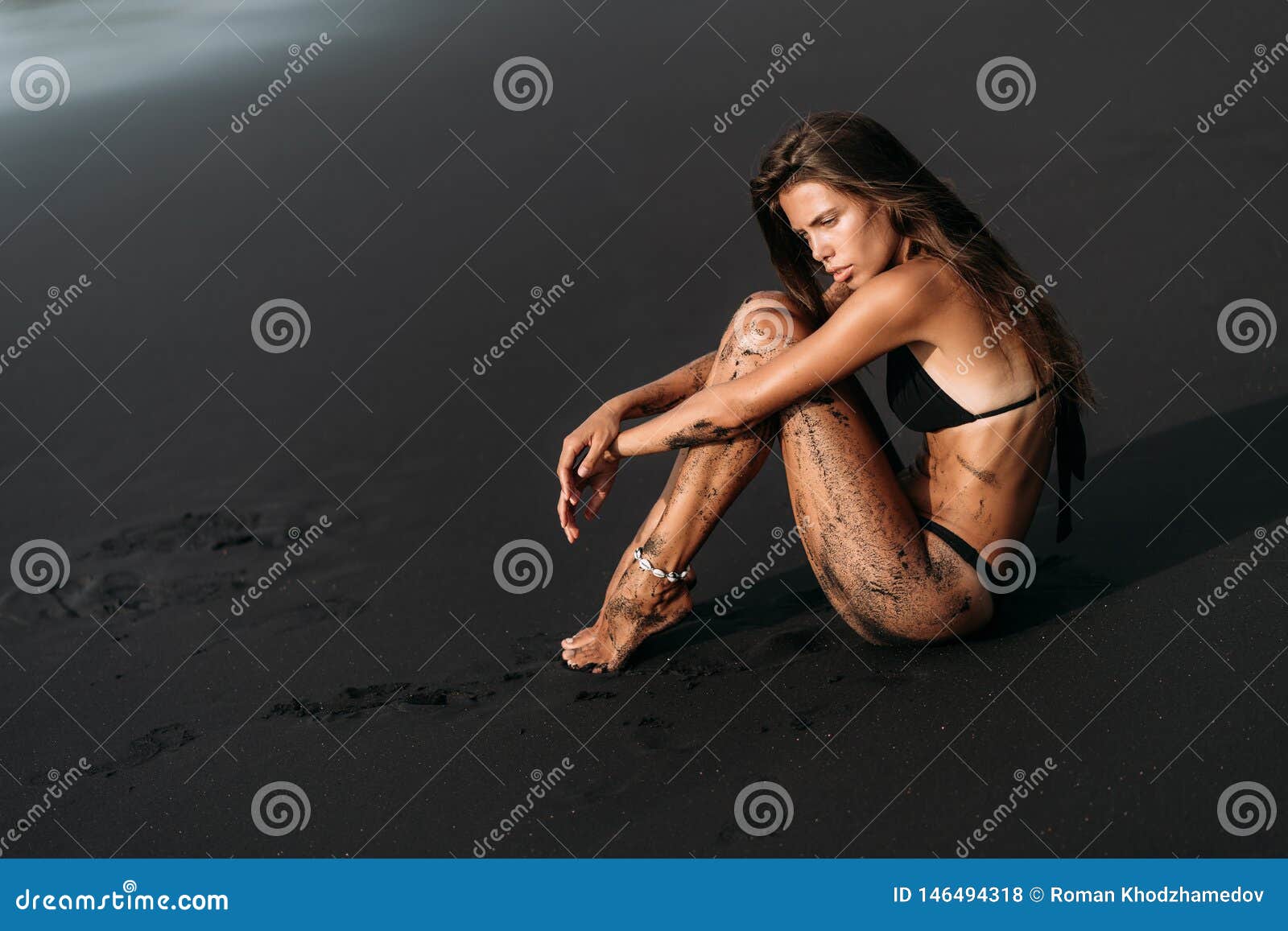 Attractive Girl In Swimwear Rests On Black Volcanic Sand Beach Stock