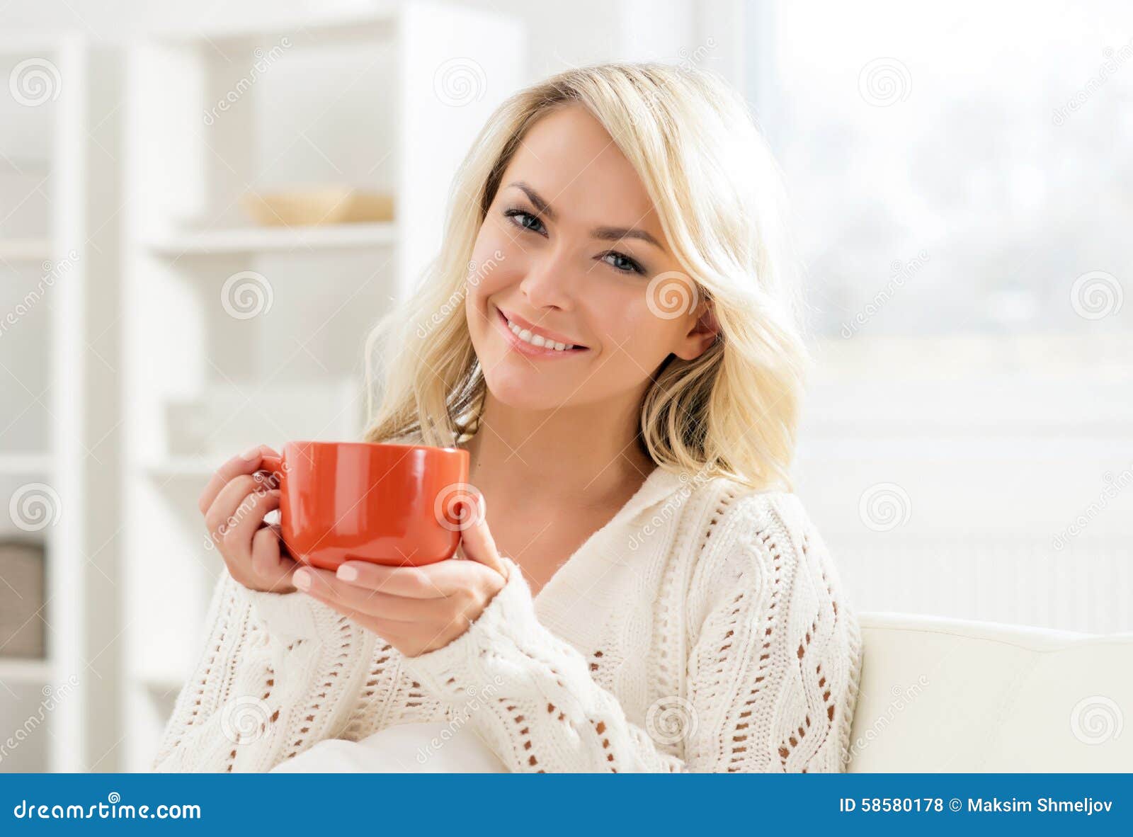 Attractive smiling girl enjoying the smell of coffee in the morning.