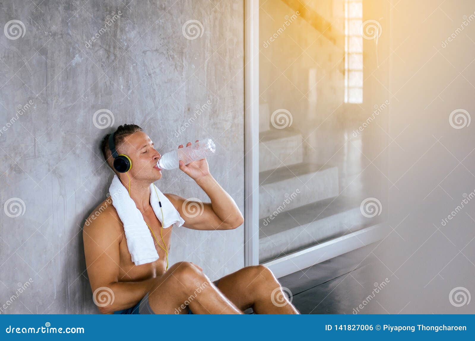 attractive sport men sitting and drinking water with break and relex after workout indoor