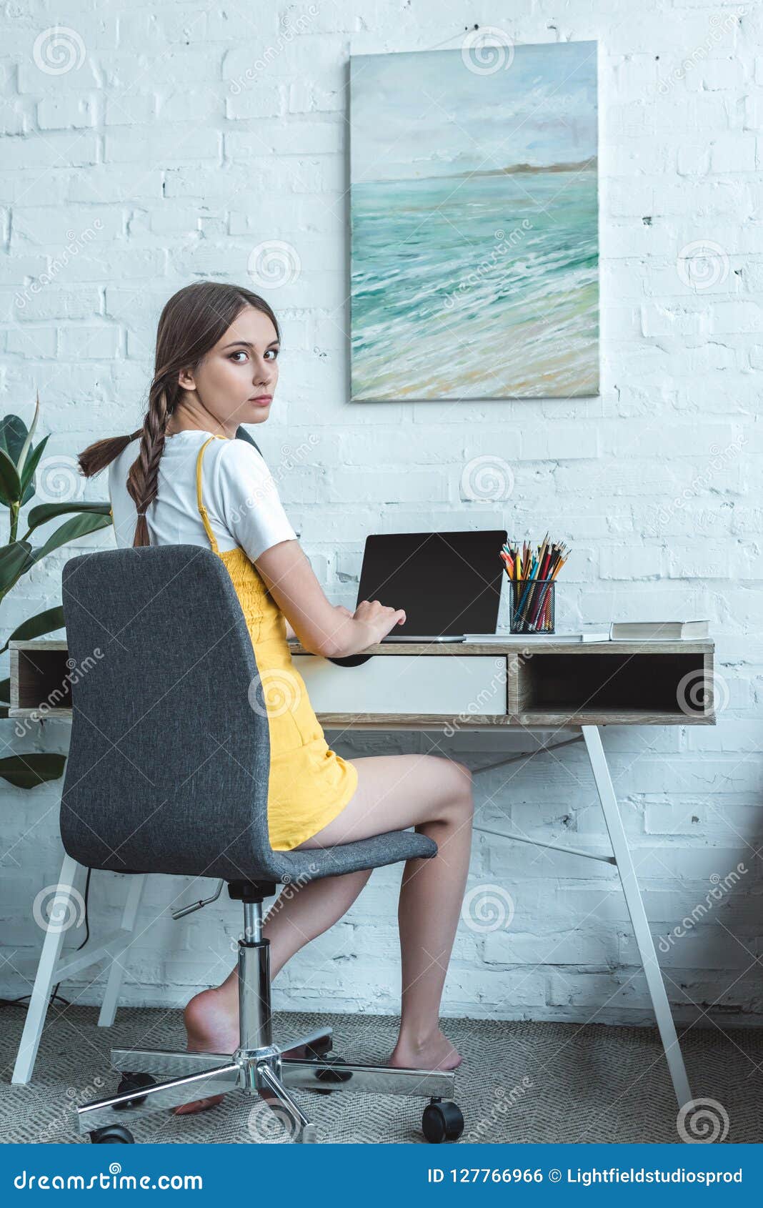 Attractive Teen Girl Using Laptop And Sitting At Table Stock Photo
